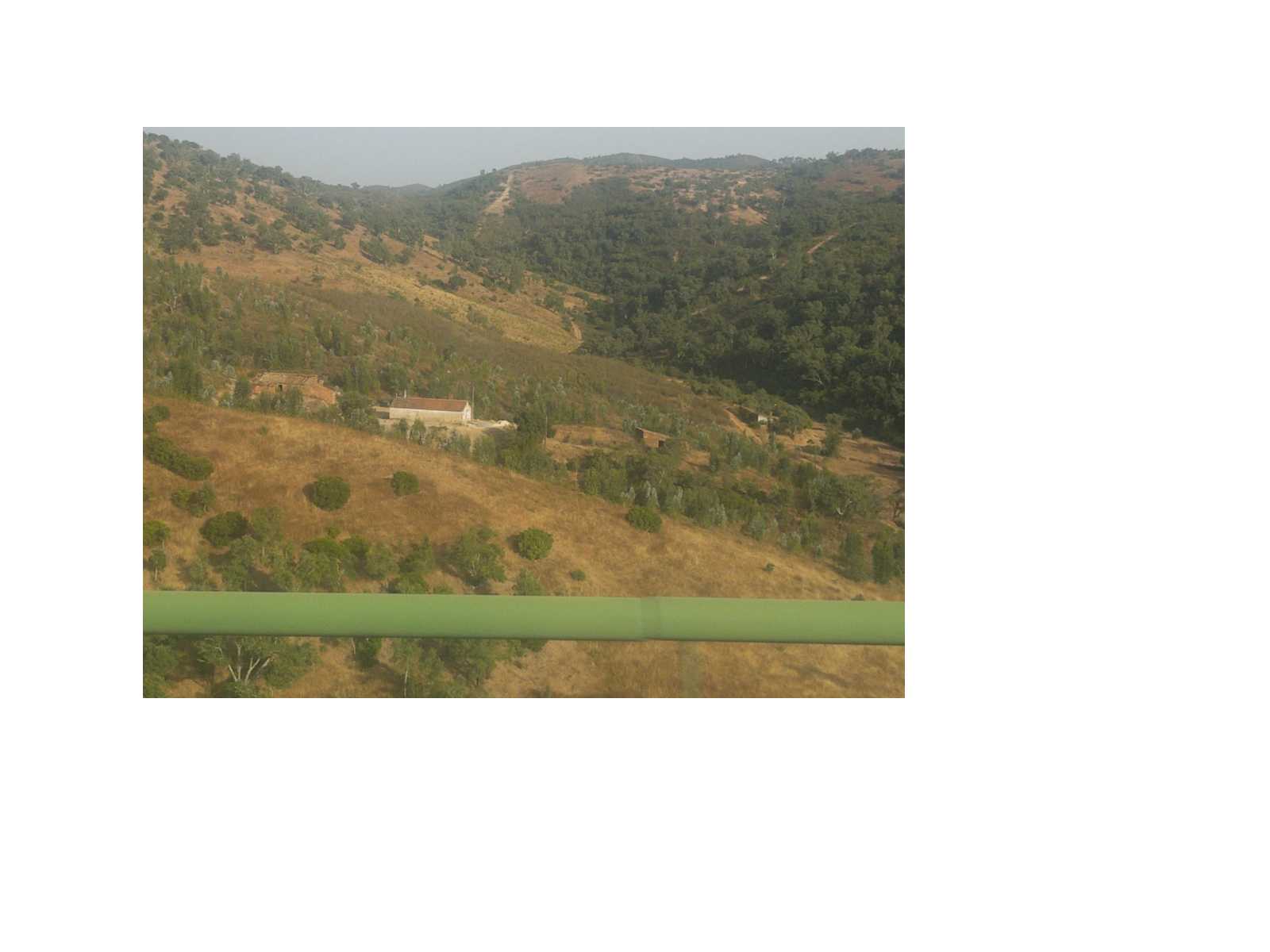 a yellow landscape, slight hills, old white portuguese building midway up the hill. Green bar across the bottom of the photo